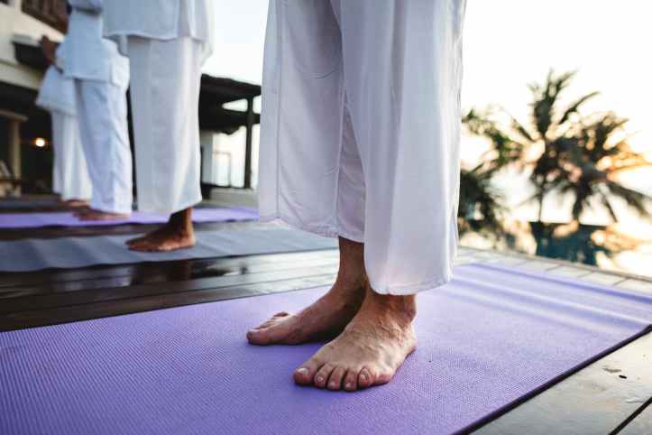 photo of people standing on purple yoga mats
