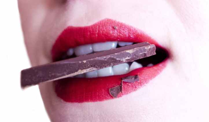 woman biting brown chocolate