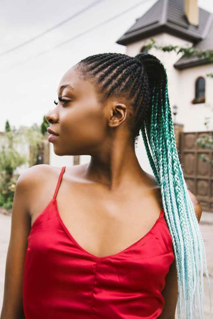 shallow focus photography of woman with braided hair and wearing red spaghetti strap top
