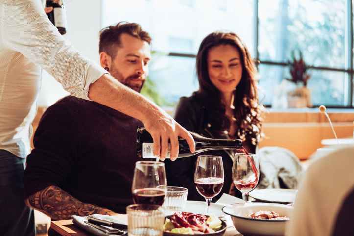 man pouring wine on glass