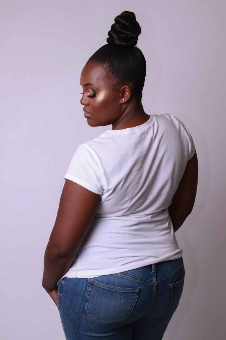 back view photo of woman in white t shirt and blue jeans posing in front of white background