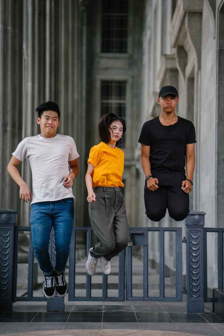 photo of two men and one woman jumping near gray gate