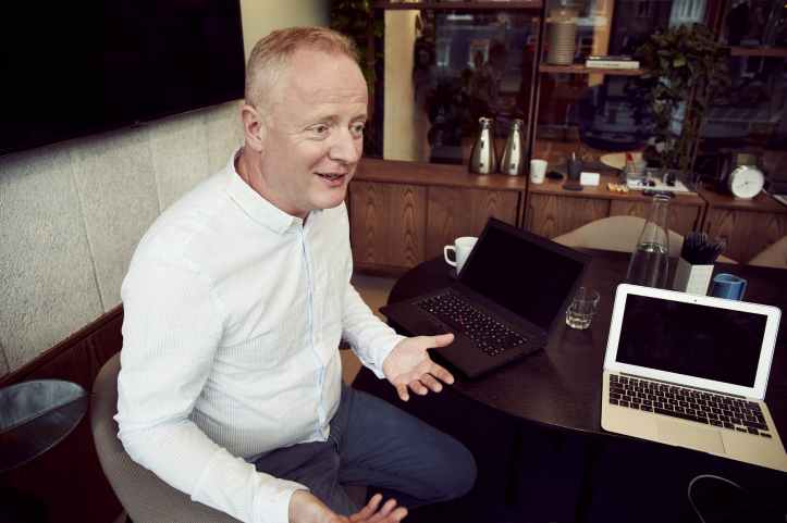 man wearing long sleeved shirt sitting beside table