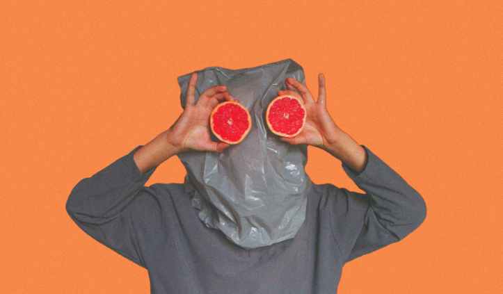 person covered with plastic bag on head while holding sliced blood orange