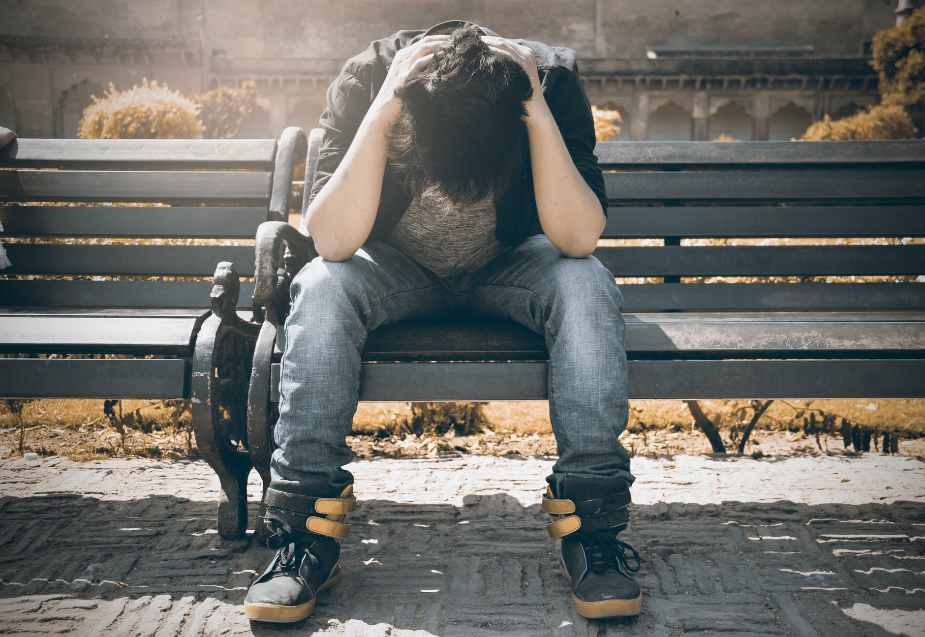 homme en chemise noire et pantalon en denim gris assis sur un banc rembourre gris