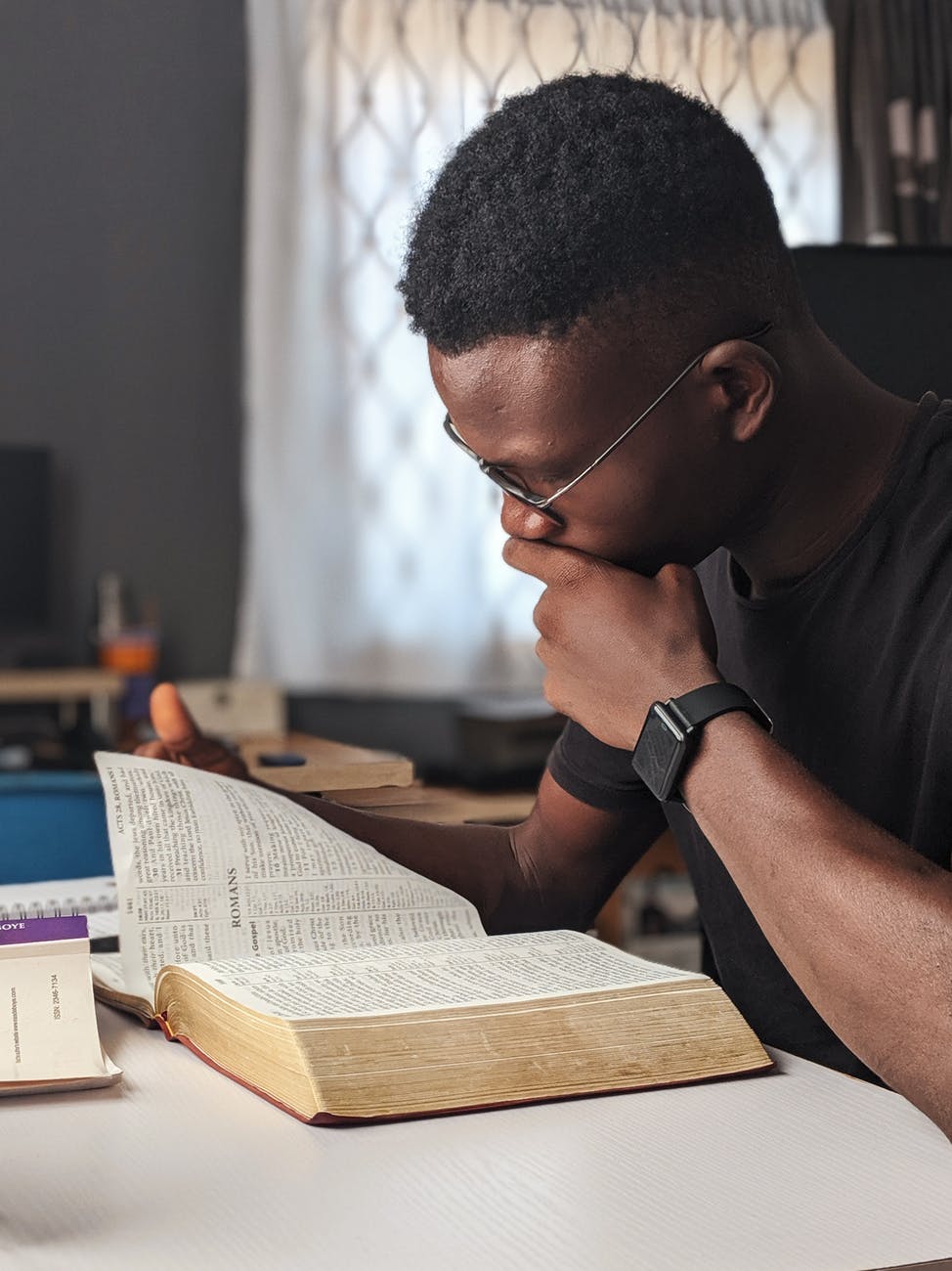 homme portant un livre de lecture chemise a col rond noir