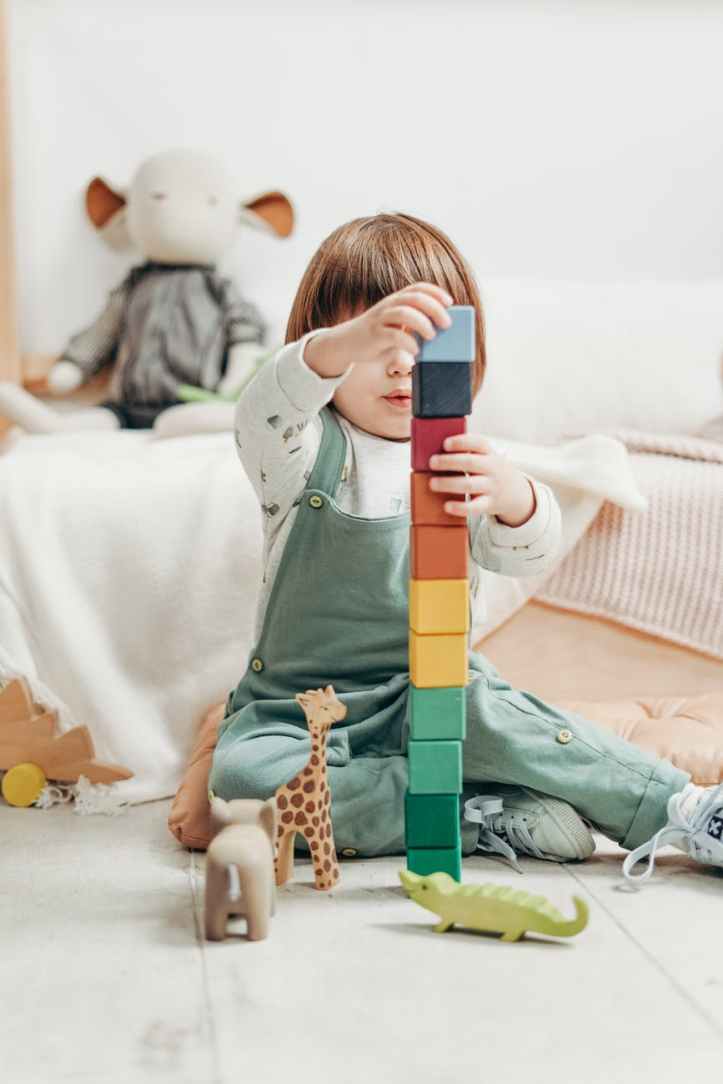 enfant en haut a manches longues blanc et pantalon salopette jouant avec des blocs lego