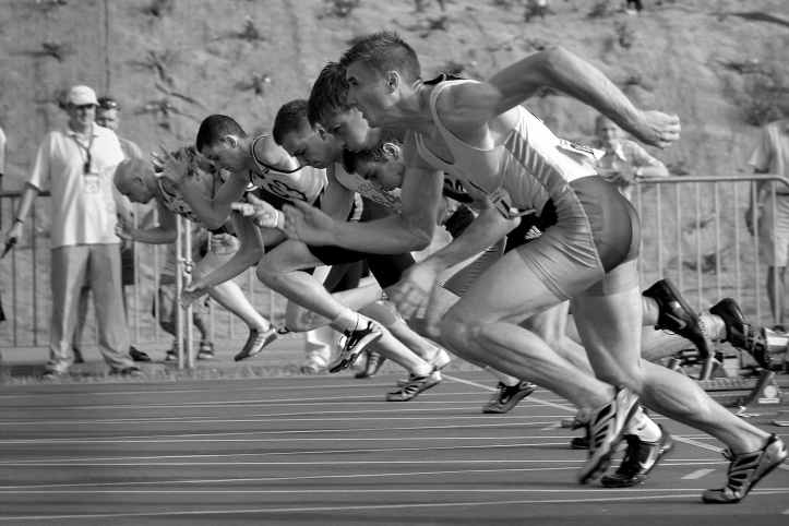 athletes qui courent sur un ovale d athletisme en photographie en niveaux de gris