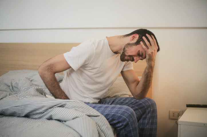 jeune homme en vetements de nuit souffrant de maux de tete le matin