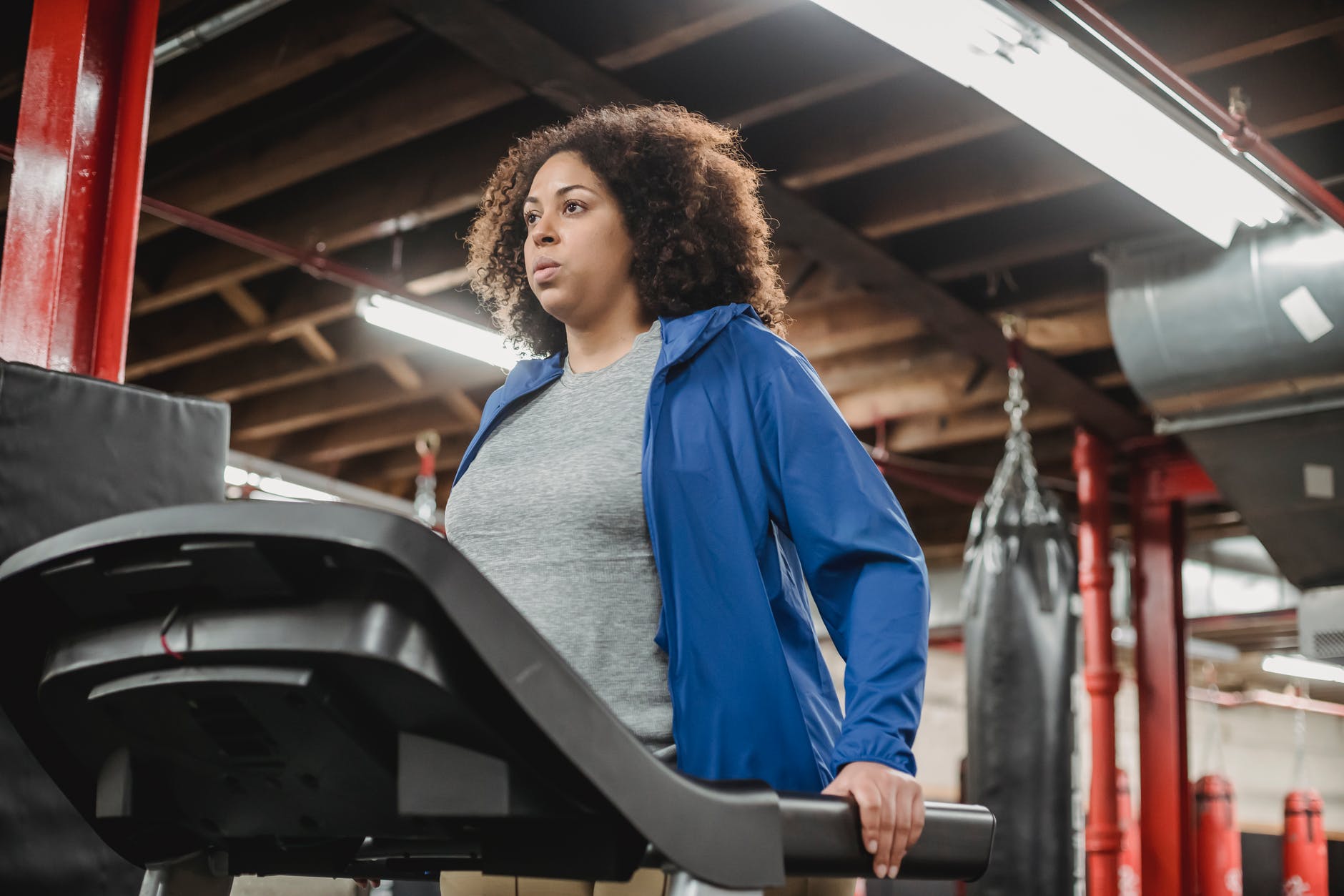 femme en veste bleue debout devant un tapis roulant noir